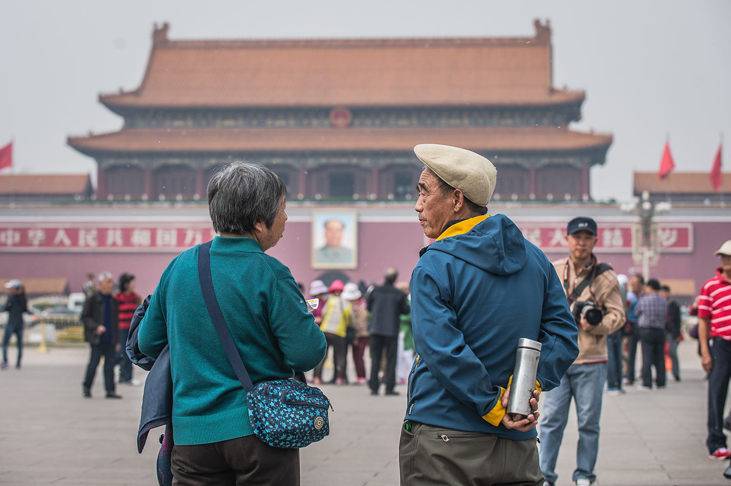 A Chinese woman and man talk in front of Tiananmen Tower in Beijing.