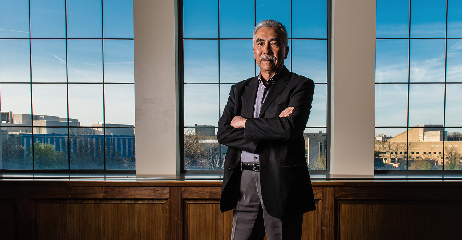 Ali Tuet poses in front of windows in the Executive Conference Room in Kelley School of Business Undergraduate Building, Hodge Hall. Through the windows you can see the Indiana University School of Global and International Studies on the left and the IU Art Museum on the right.