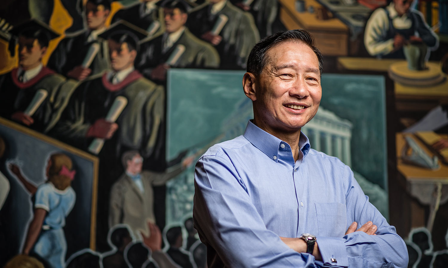 Peter Wong poses in front of a mural in Indiana University’s Lilly House.