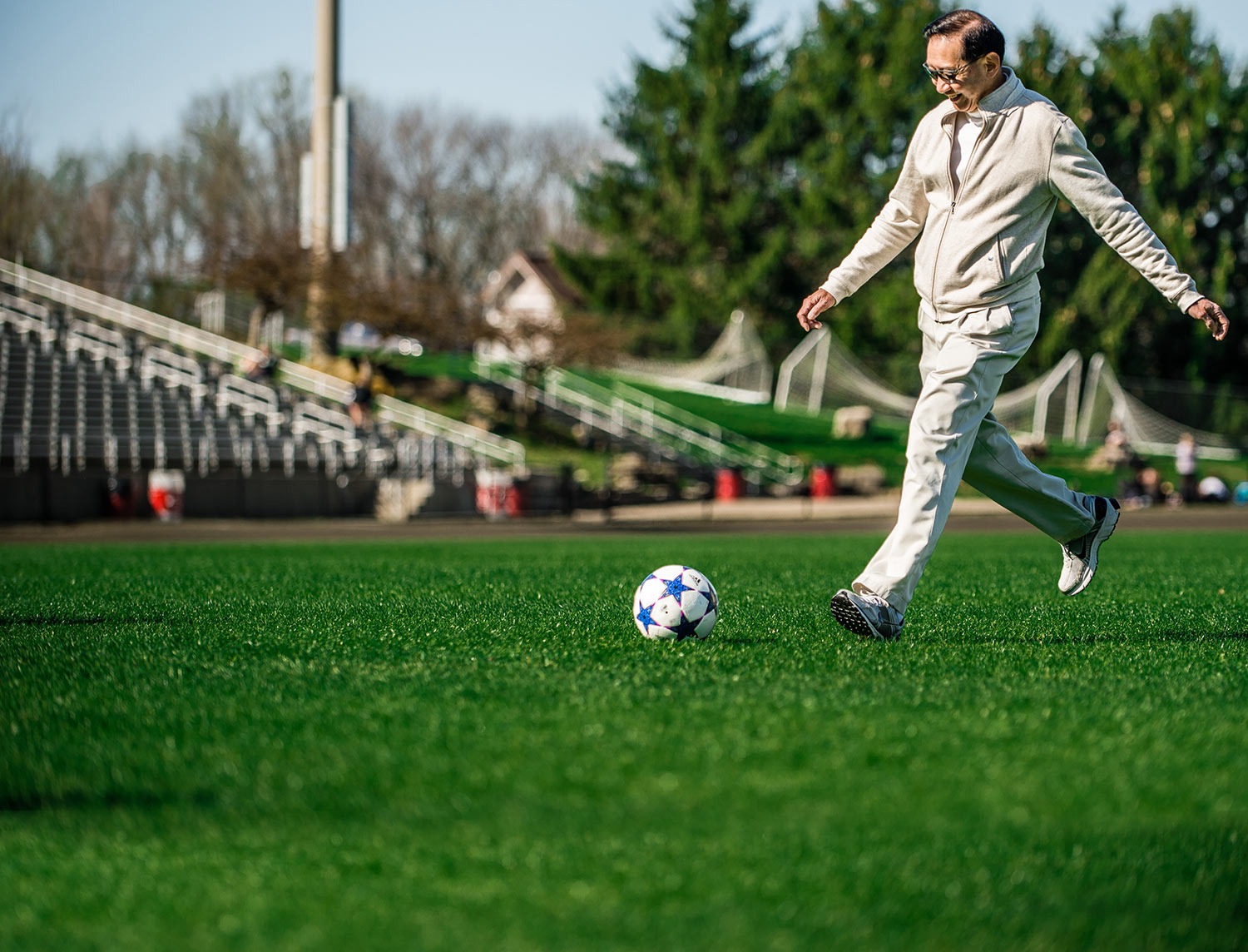 Peter Wong kicks a soccer ball on the IU soccer practice field.