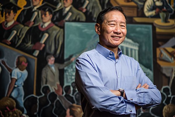 Peter Wong poses in front of a mural in Indiana University’s Lilly House.